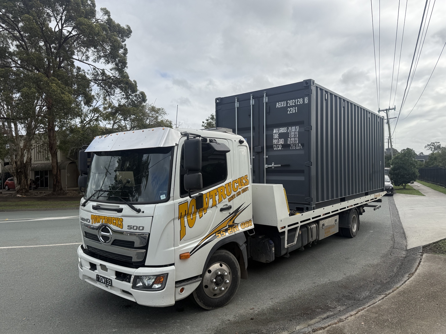 Shipping container loaded onto a tilt tray delivery truck